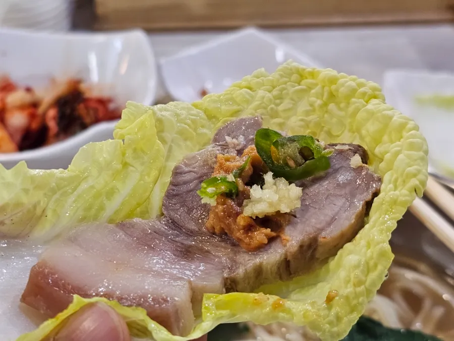 Slice of Korean boiled pork wrapped in napa cabbage at Andongjip