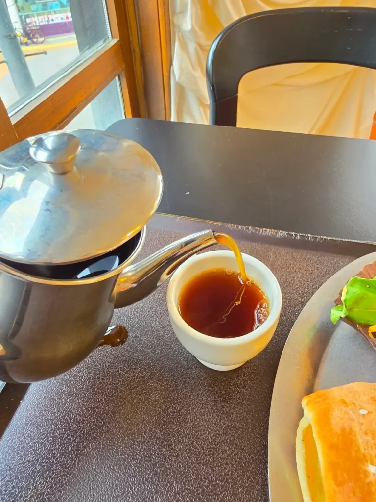 Decaf Americano being poured from a metal coffee pot into a small cup