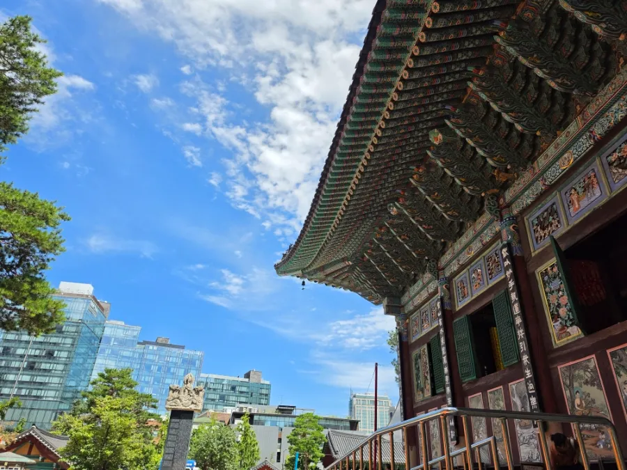 Traditional roof of Daeungjeon Hall at Jogyesa Temple beside modern buildings