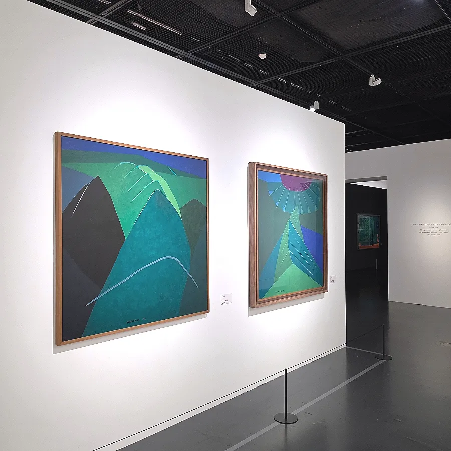 Green and blue mountain paintings by Yoo Youngkuk displayed in the gallery