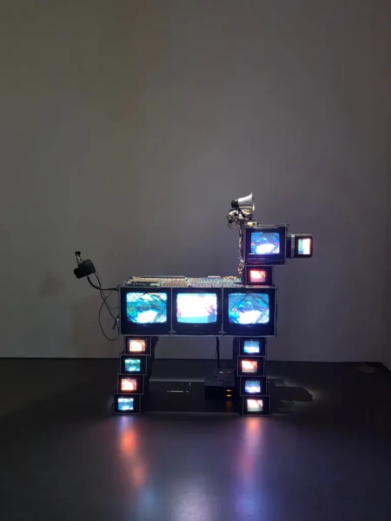 Paik Nam June video sculpture assembled from small television monitors, electronic equipment and a horn-shaped speaker.