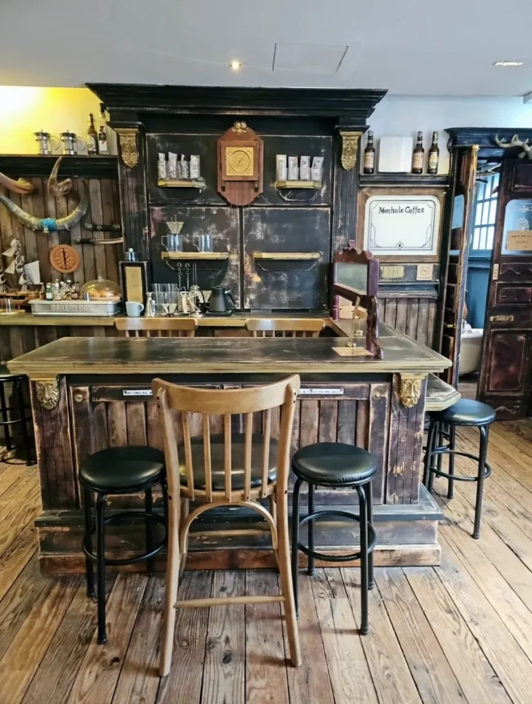 Vintage wooden bar counter with stools, cups and bottles at Manhole Coffee Western Book Cafe.