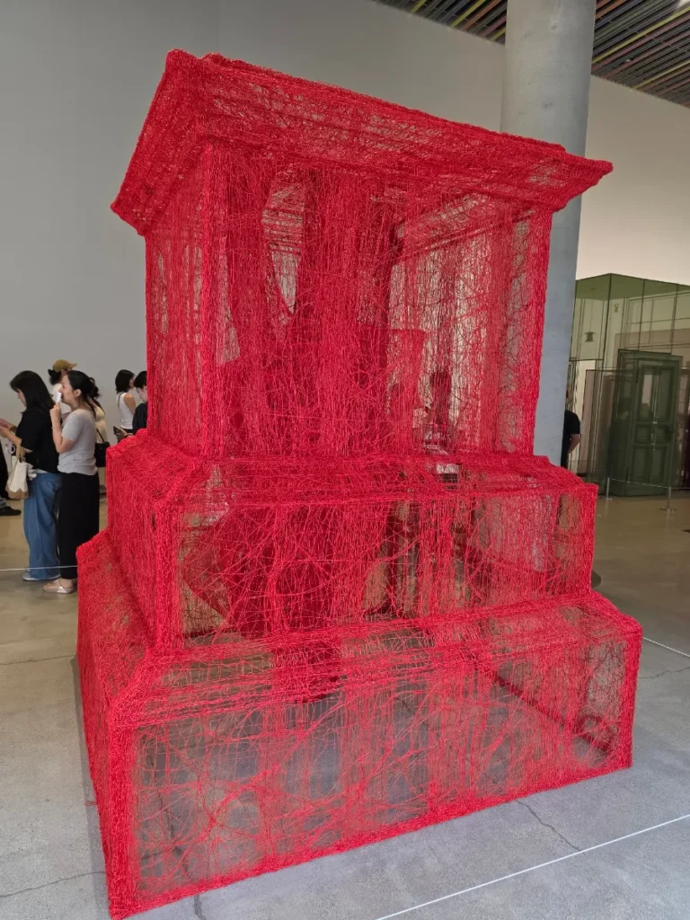 Red translucent fabric house by Do Ho Suh
