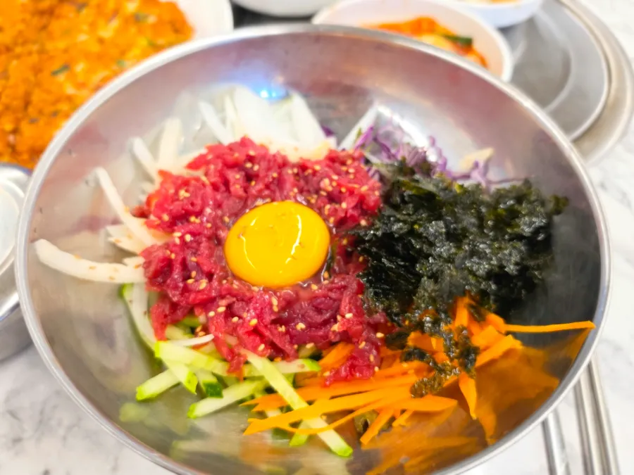 Korean yukhoe bibimbap with raw beef, vegetables, seaweed, and egg yolk