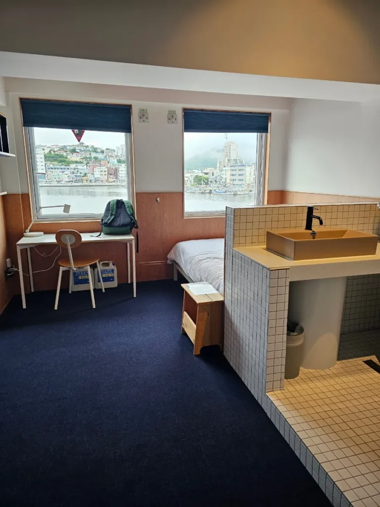 Guest room at Local Stitch Tongyeong with a desk, bed and harbor-facing windows